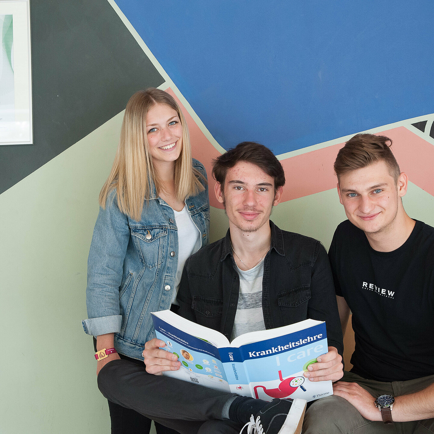 Eine Schülerin und zwei Schüler, die gerade ihre Ausbildung an der kbo-Berufsfachschule für Pflege absolvieren