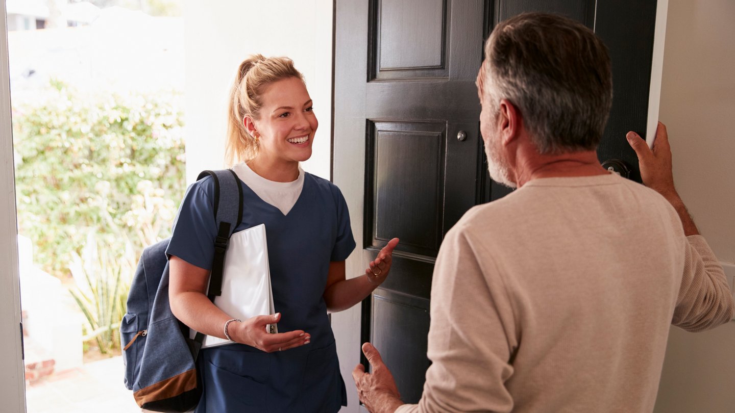 Senior man opening his front door to a female healthcare worker making a home health visit Senior man opening his front door to a female healthcare worker making a home health visit