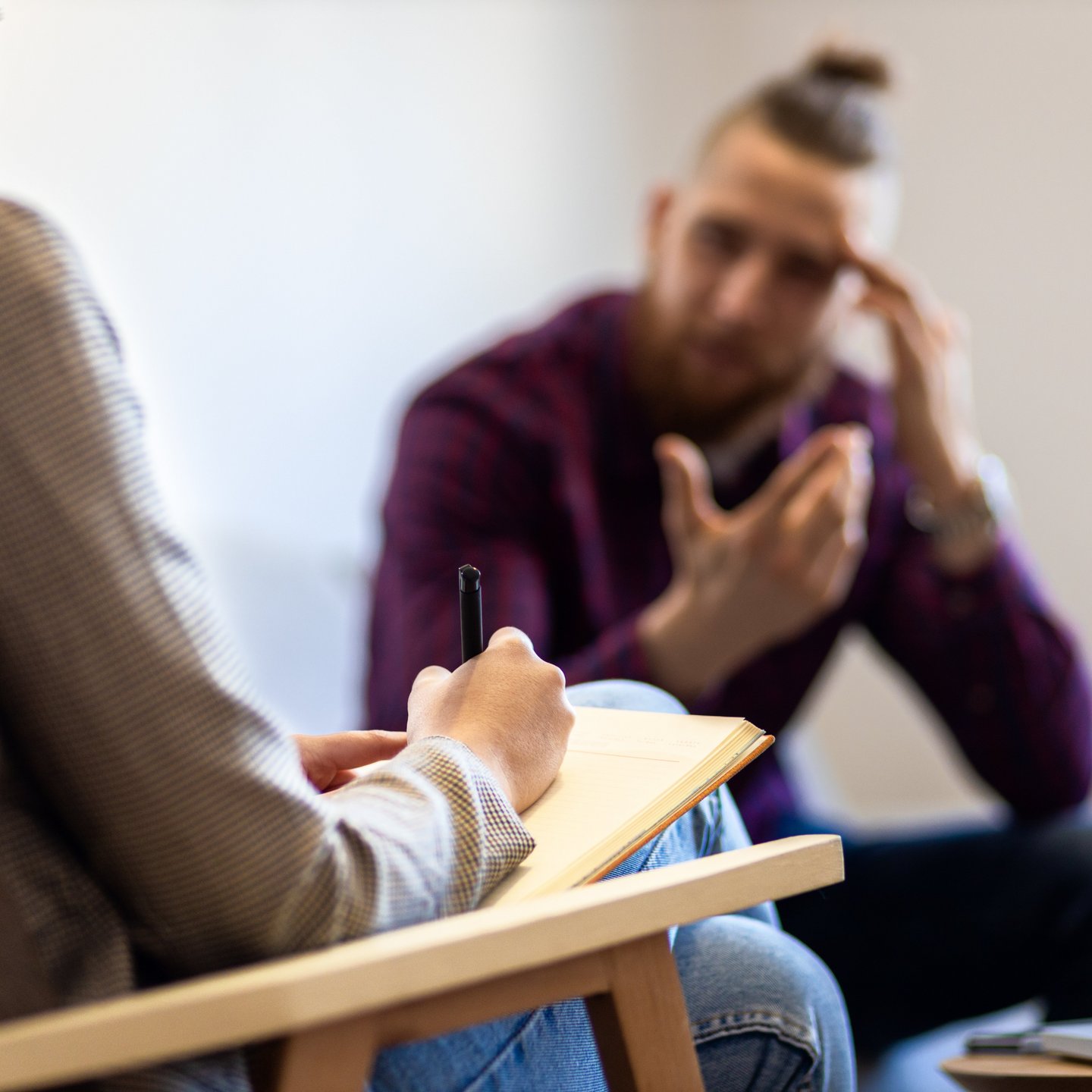 Young man talking to female psychologist during session.