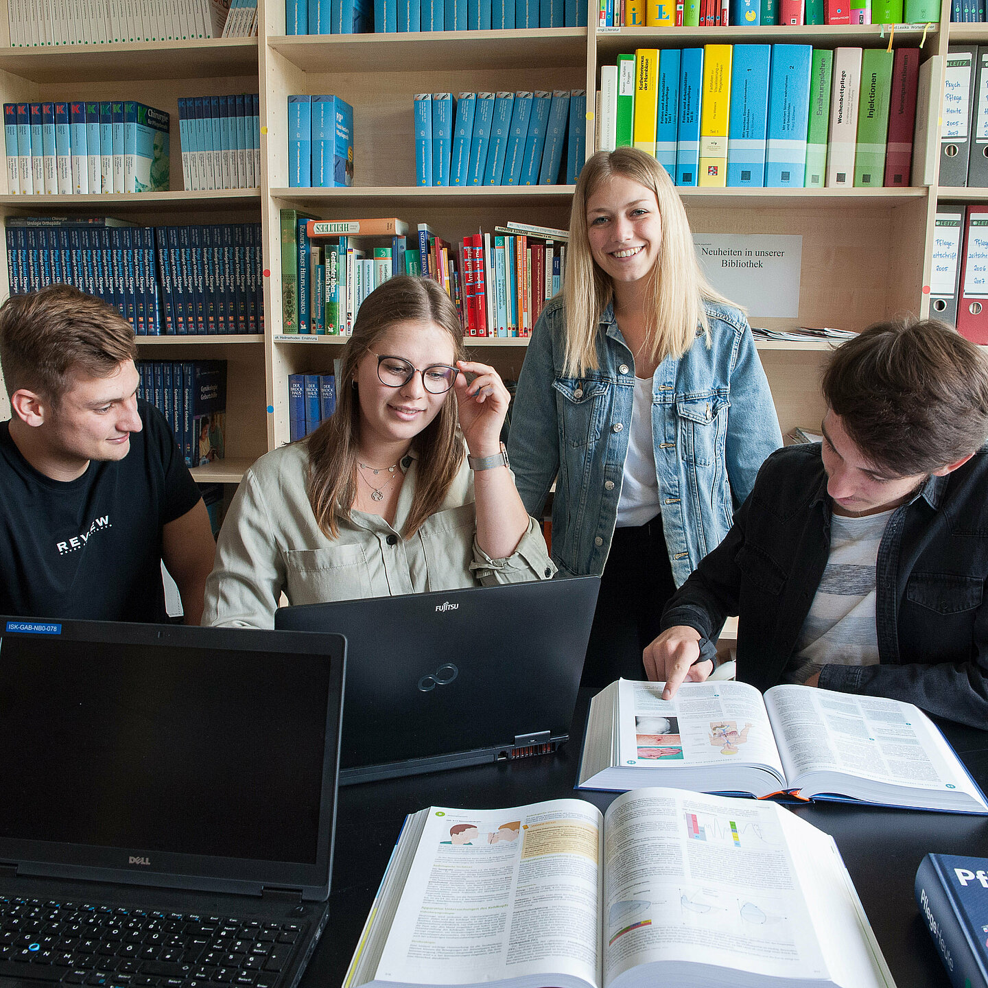 Vier Auszubildende sitzen in der Bibliothek und lernen gemeinsam